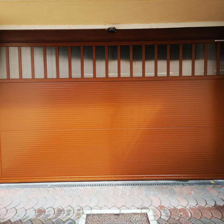 Installazione di SecureMe, porta basculante di sicurezza per garage in serie in versione coibentata, verniciata marrone chiaro. Adatta per sprechi di calore e locali riscaldati.